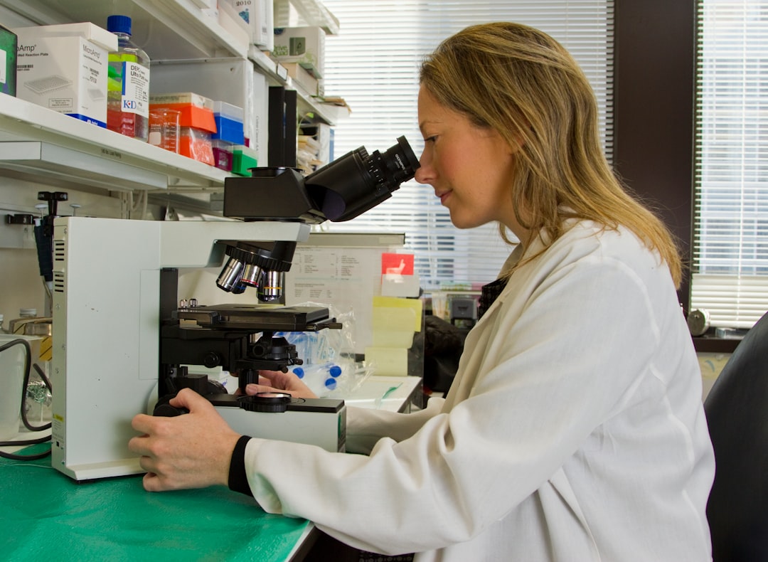 A female scientist in a laboratory looks through a microscope.