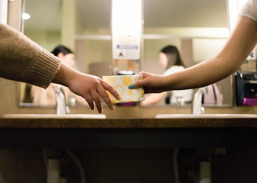 A woman passes a menstrual product to another.